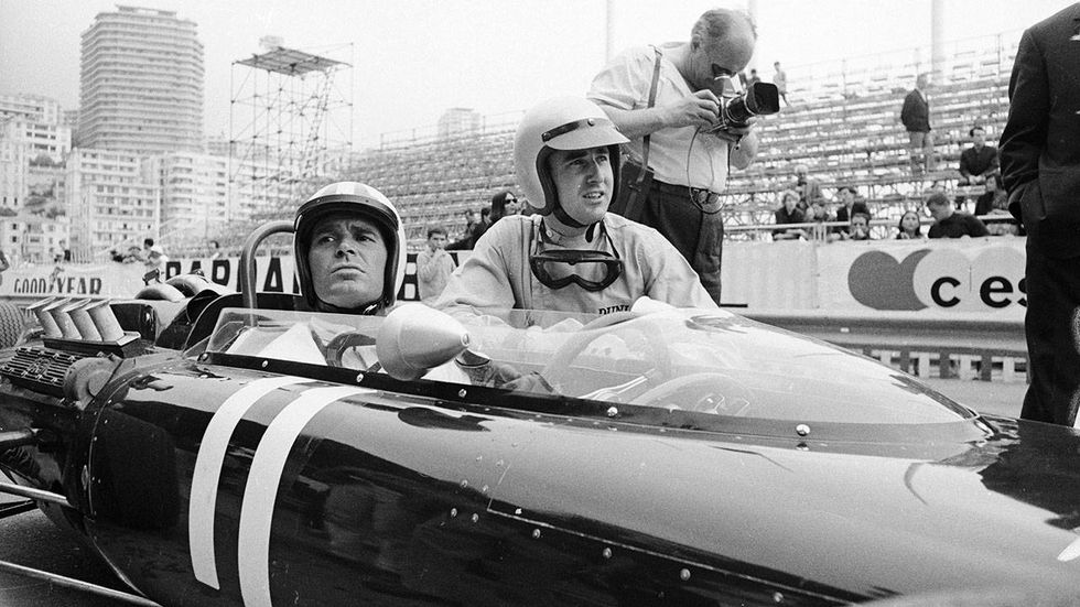 May 20, 1966 American actor James Garner in a race car at Monaco while shooting Grand Prix.  Kneeling beside him is Ferrari driver Lorenzo Bandini