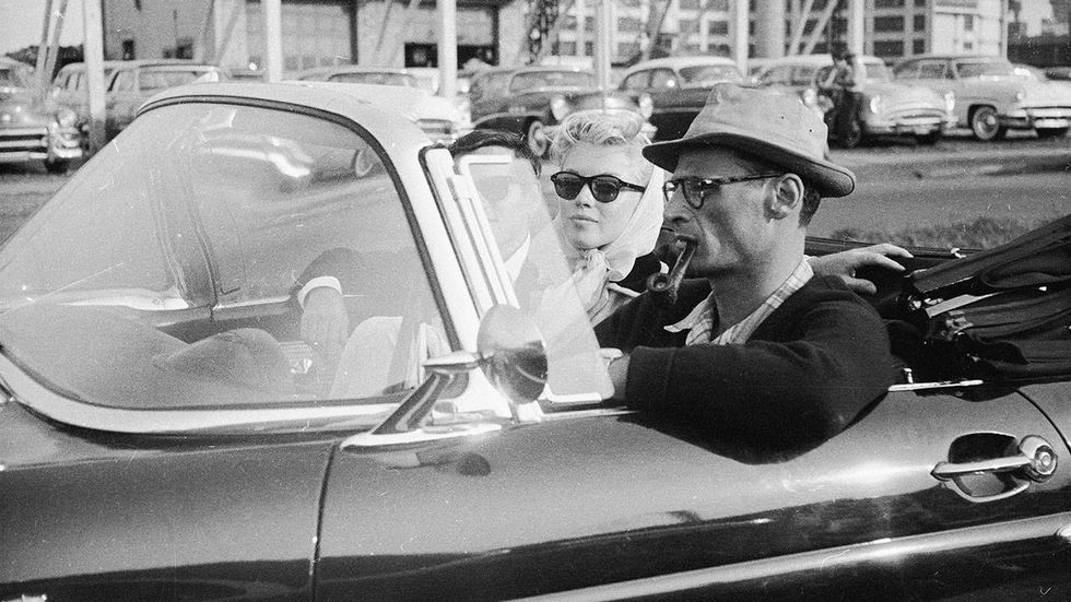 American actress Marilyn Monroe (1926-1962) rides in a car with her husband, the American playwright Arthur Miller (1915-2005),and Monroe's friend, American photographer Milton Greene (1922-1985) in New York, New York, 1956. They are driving in a 1956 Ford Thunderbird.
